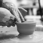 Hands shaping a clay pot on the potter’s wheel.