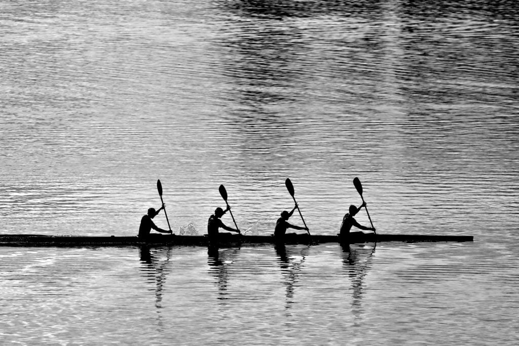 A quartet of rowers, paddling in a synchronized fashion.