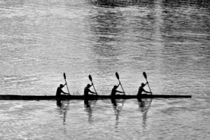 A quartet of rowers, paddling in a synchronized fashion.
